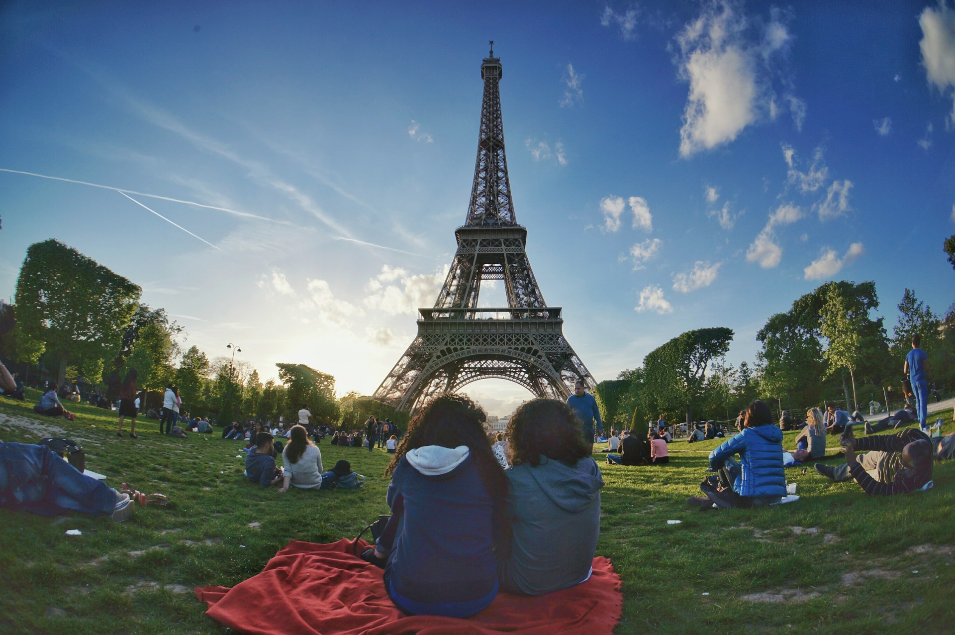 Jóvenes descansando en el césped del Campo de Marte con la Torre Eiffel al fondo