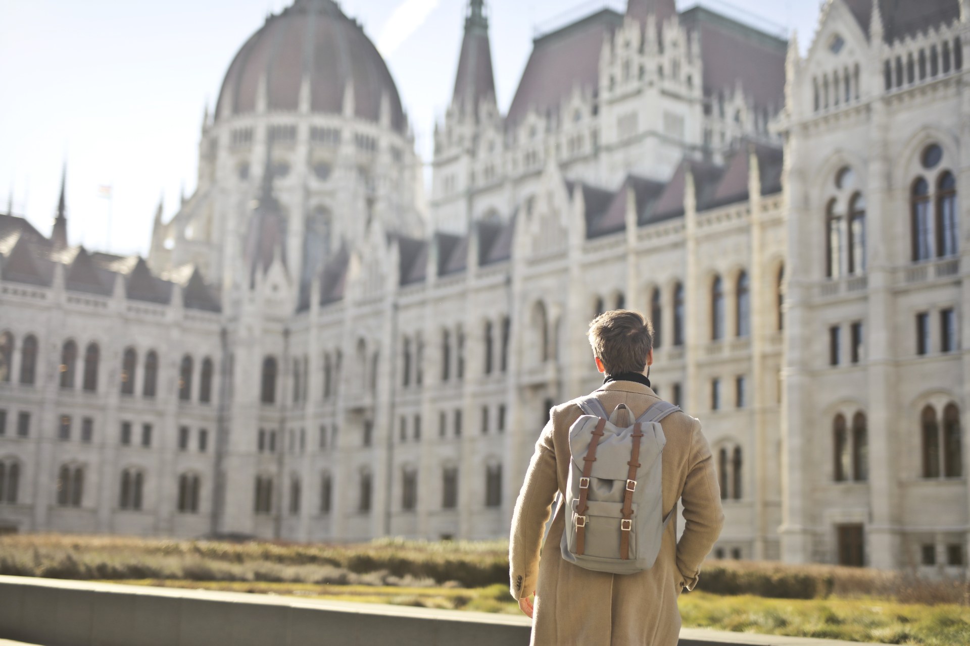 Joven con mochila frente al edificio del Parlamento de Hungría en Budapest