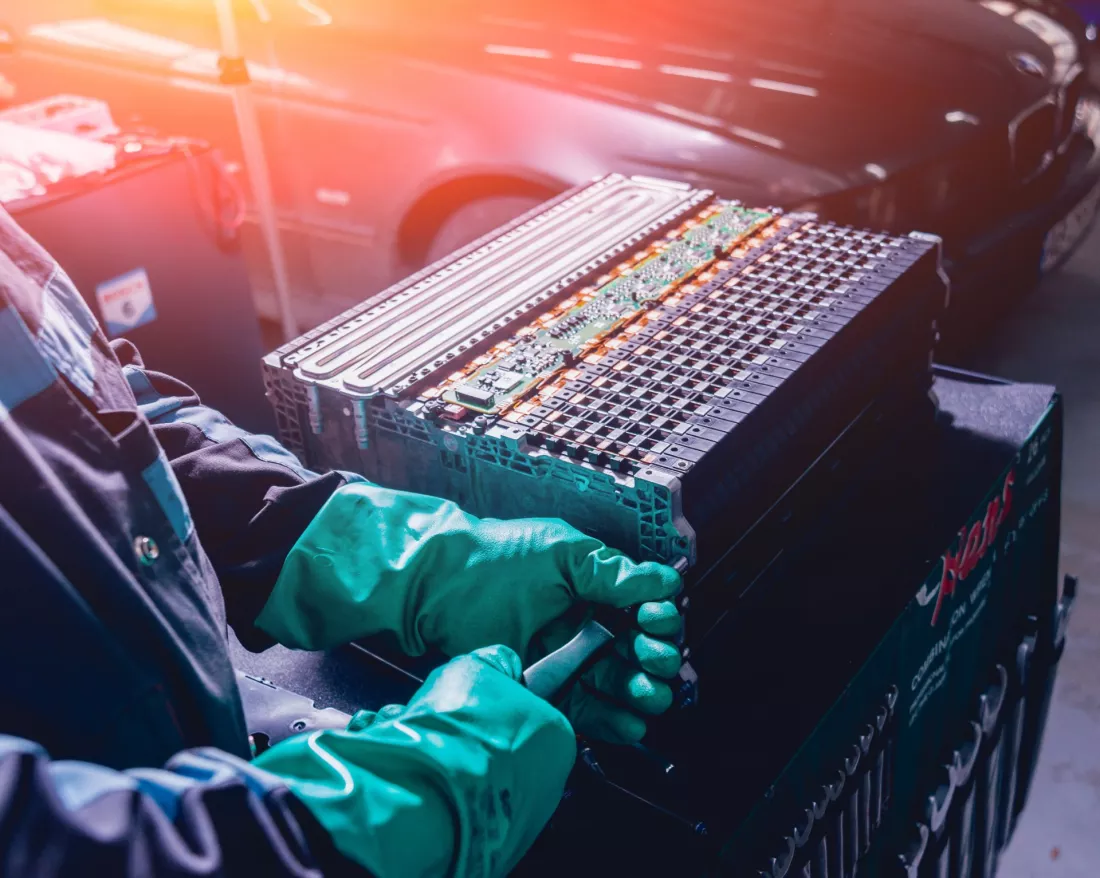 Manos con guantes desmontan la bateria de un coche electrico