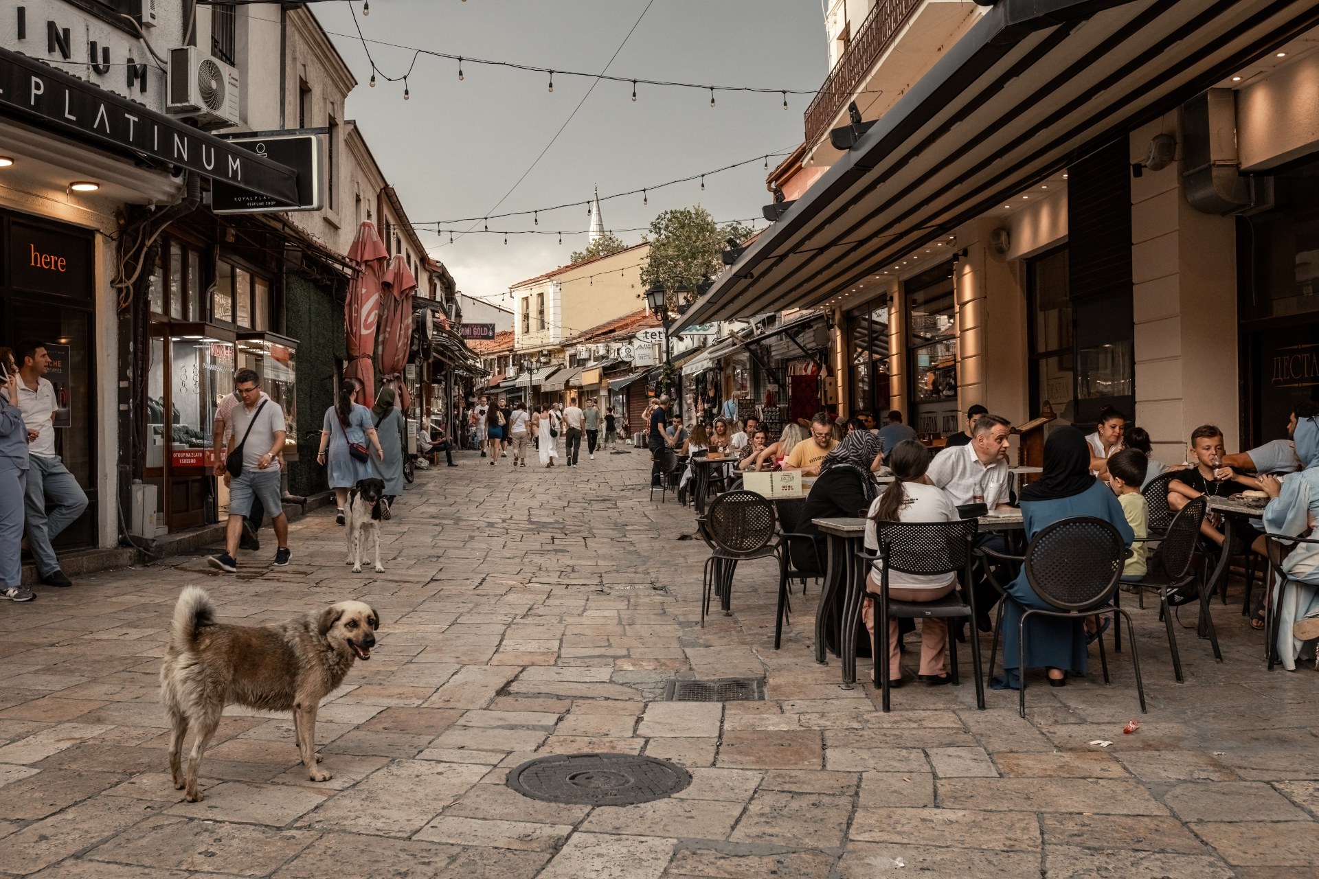 Gente en las terrazas de los cafés de una estrecha calle comercial del casco antiguo de Skopie