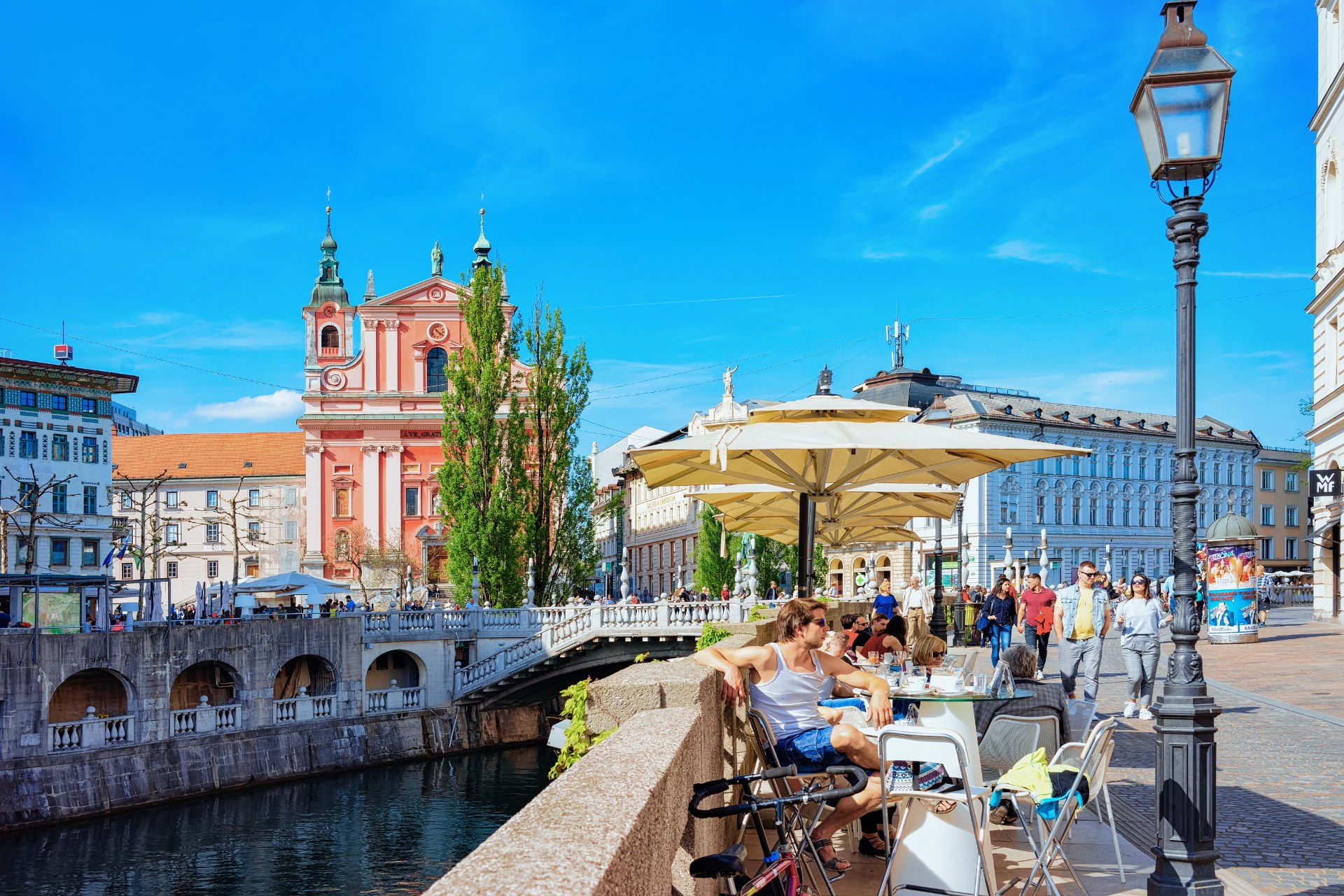 Personas en la terraza de un café en el Puente Triple, junto al río Ljubljanica, en Liubliana
